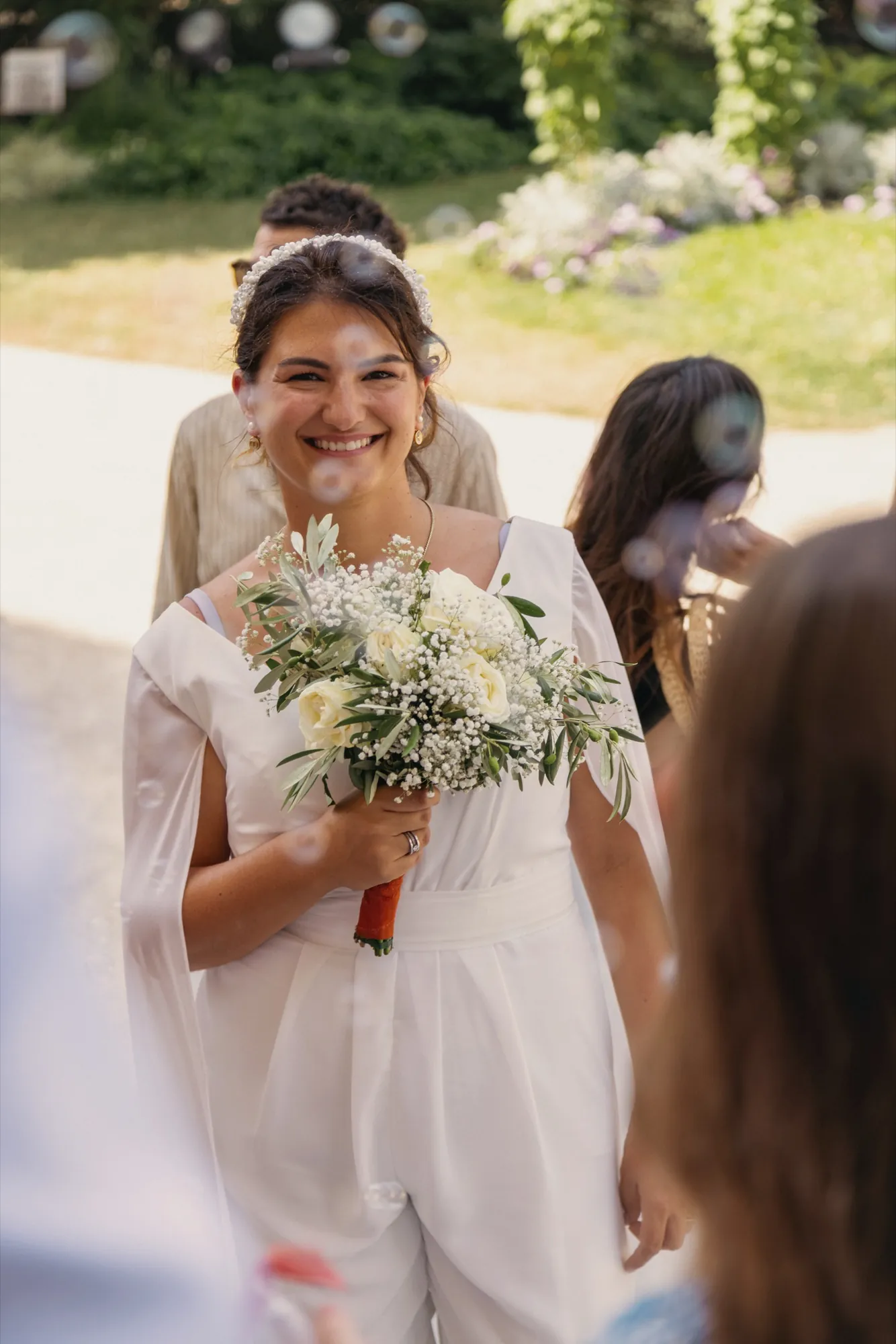 Mariée souriante tenant son bouquet, entourée de bulles de savon