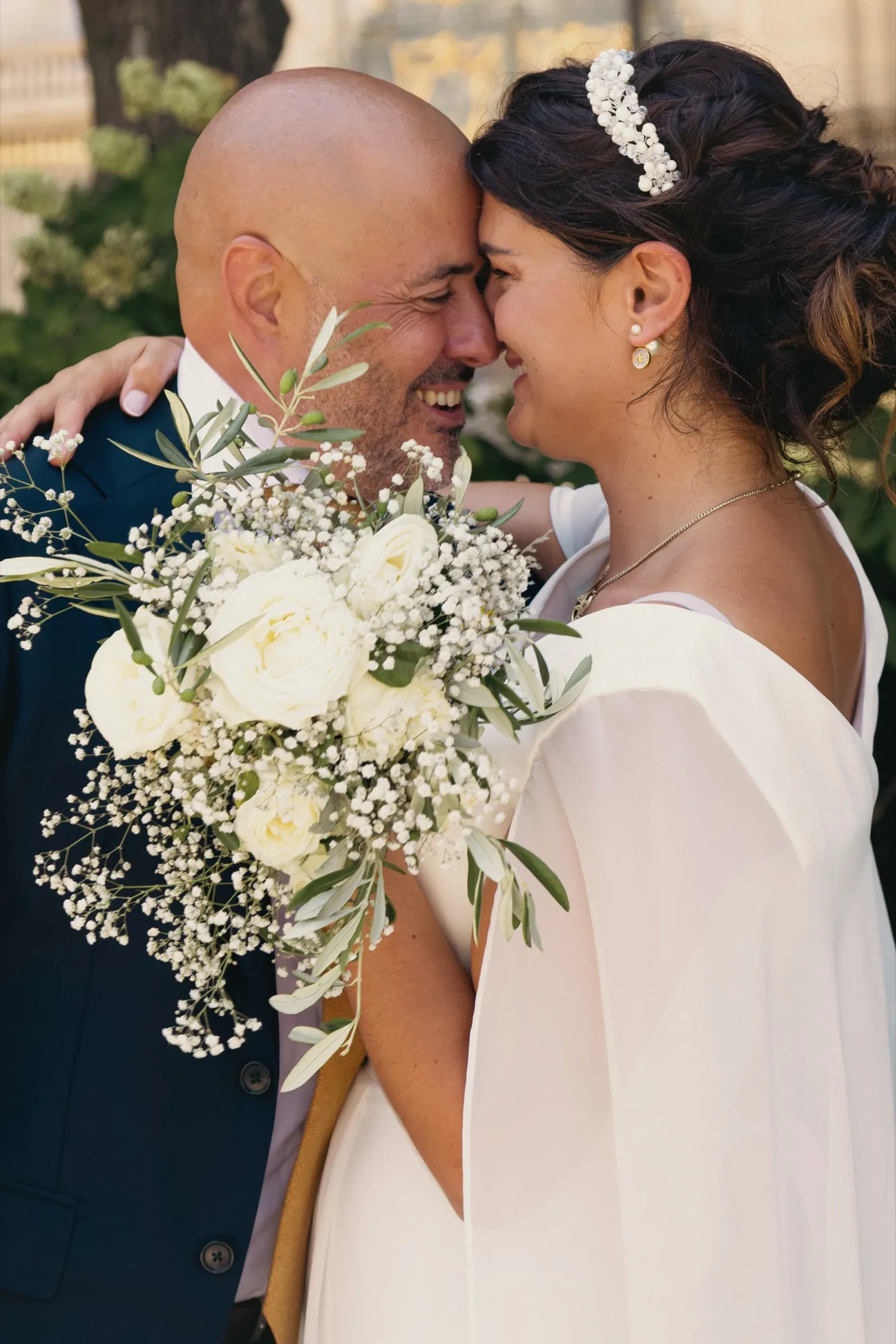 Couple de mariés front contre front, bouquet blanc au premier plan